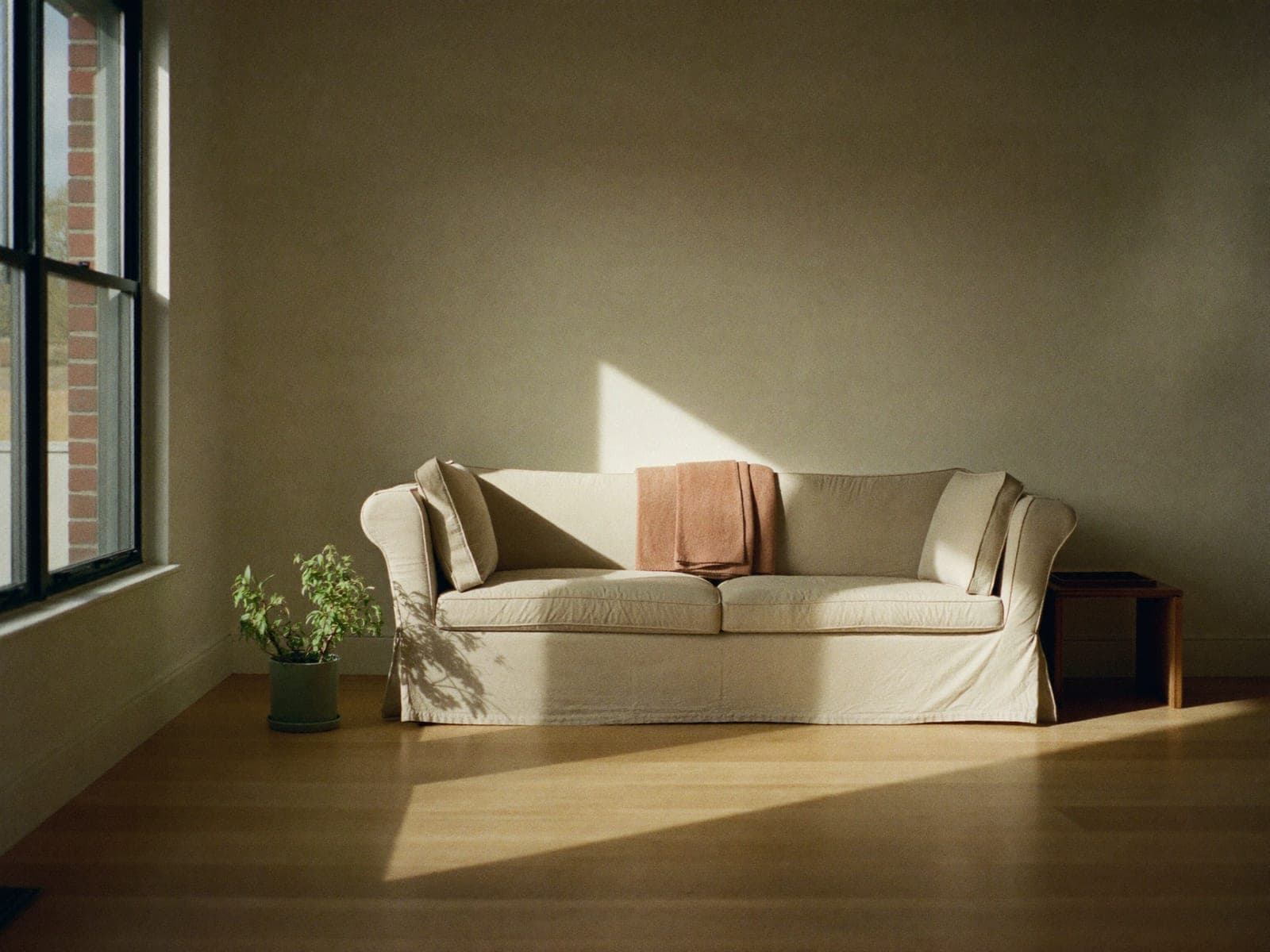 Morning light moving slowly across a clean, quiet living room with polished surfaces and folded linens.