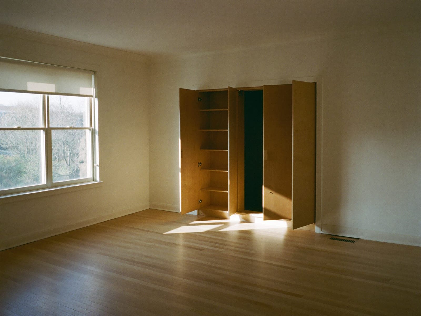 An empty apartment with bare floors and open cabinets, ready for the next resident.